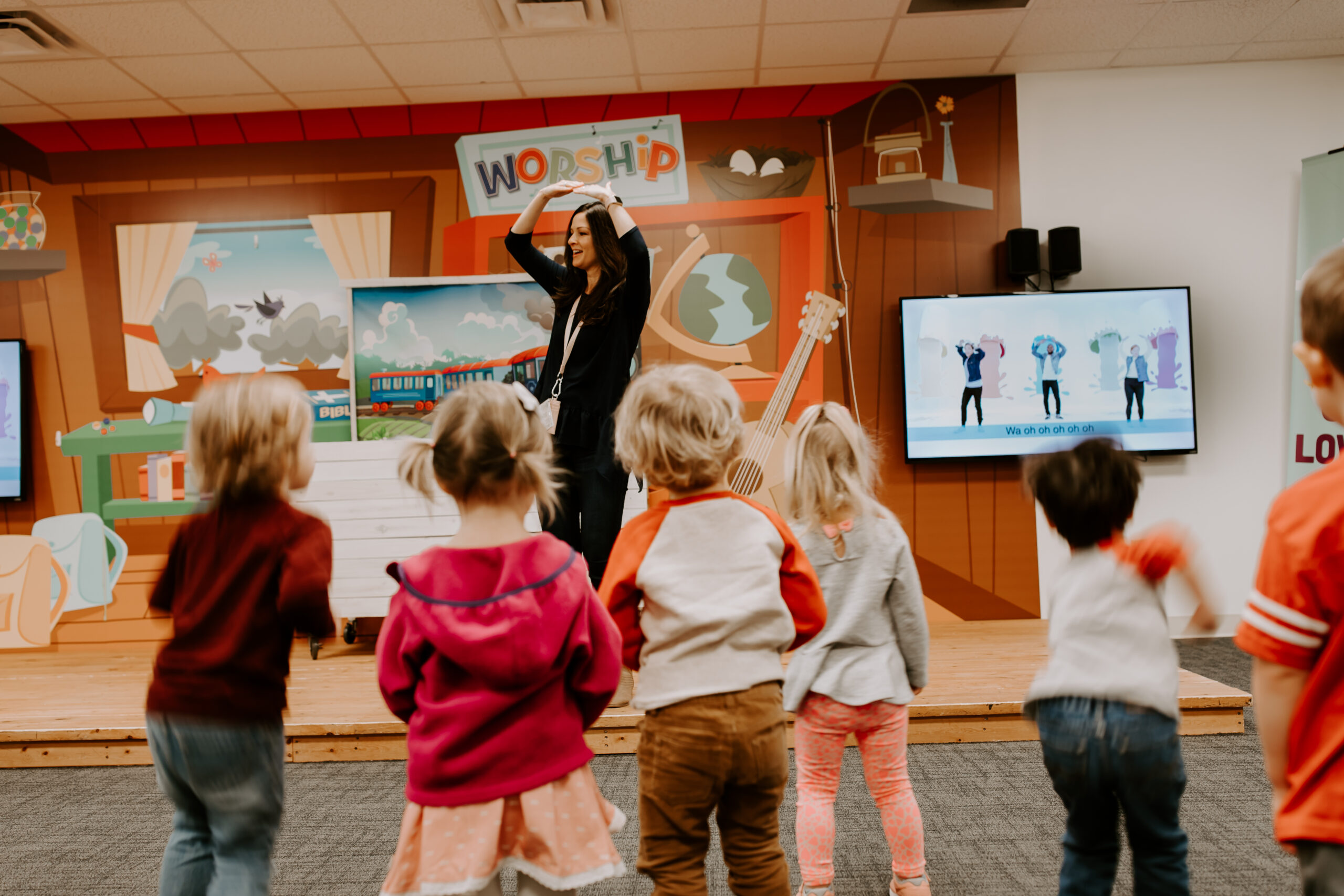 A teacher leading a preschool class in a song and dance