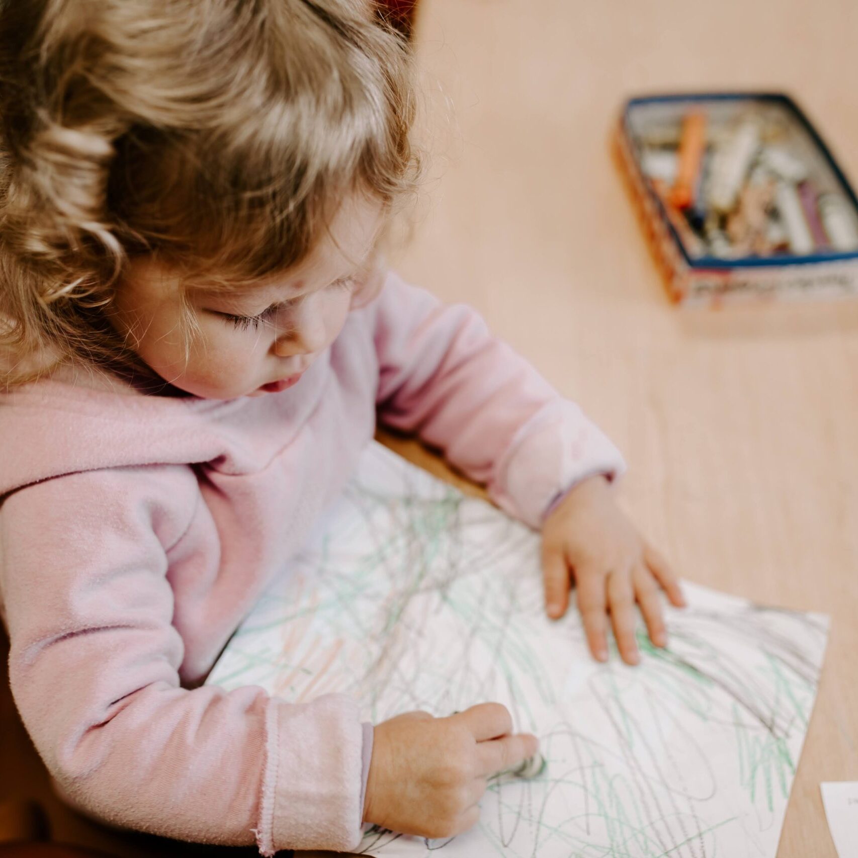 A young girl drawing with a crayon