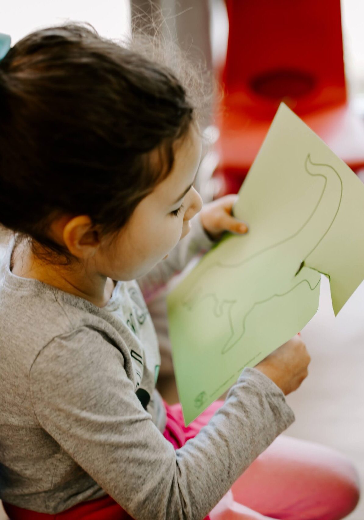 A girl cutting out a dinosaur