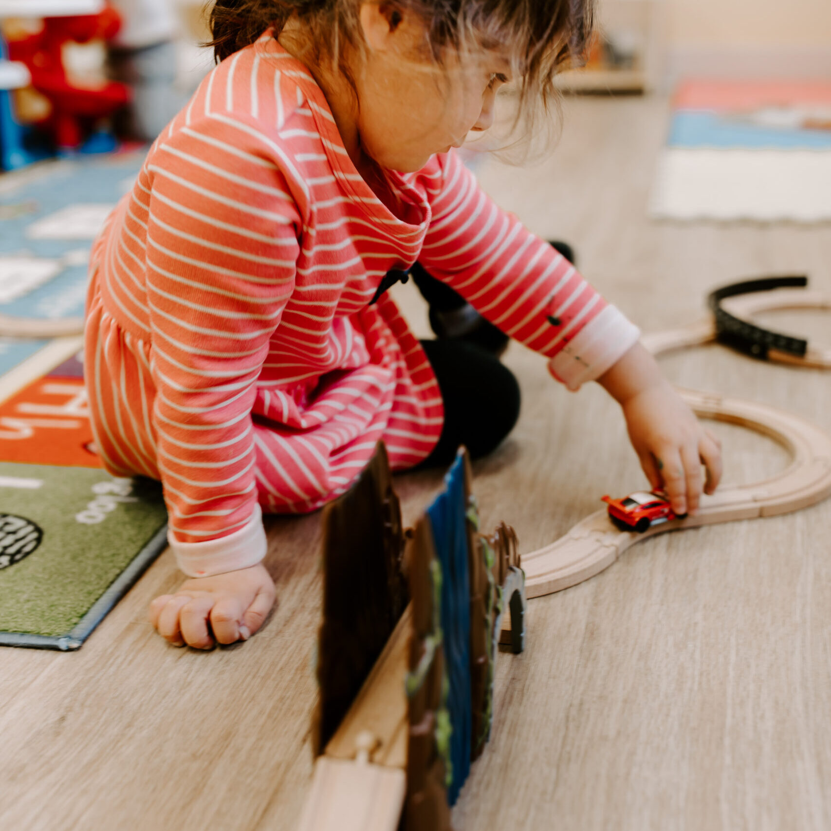 A young girl playing with a toy car
